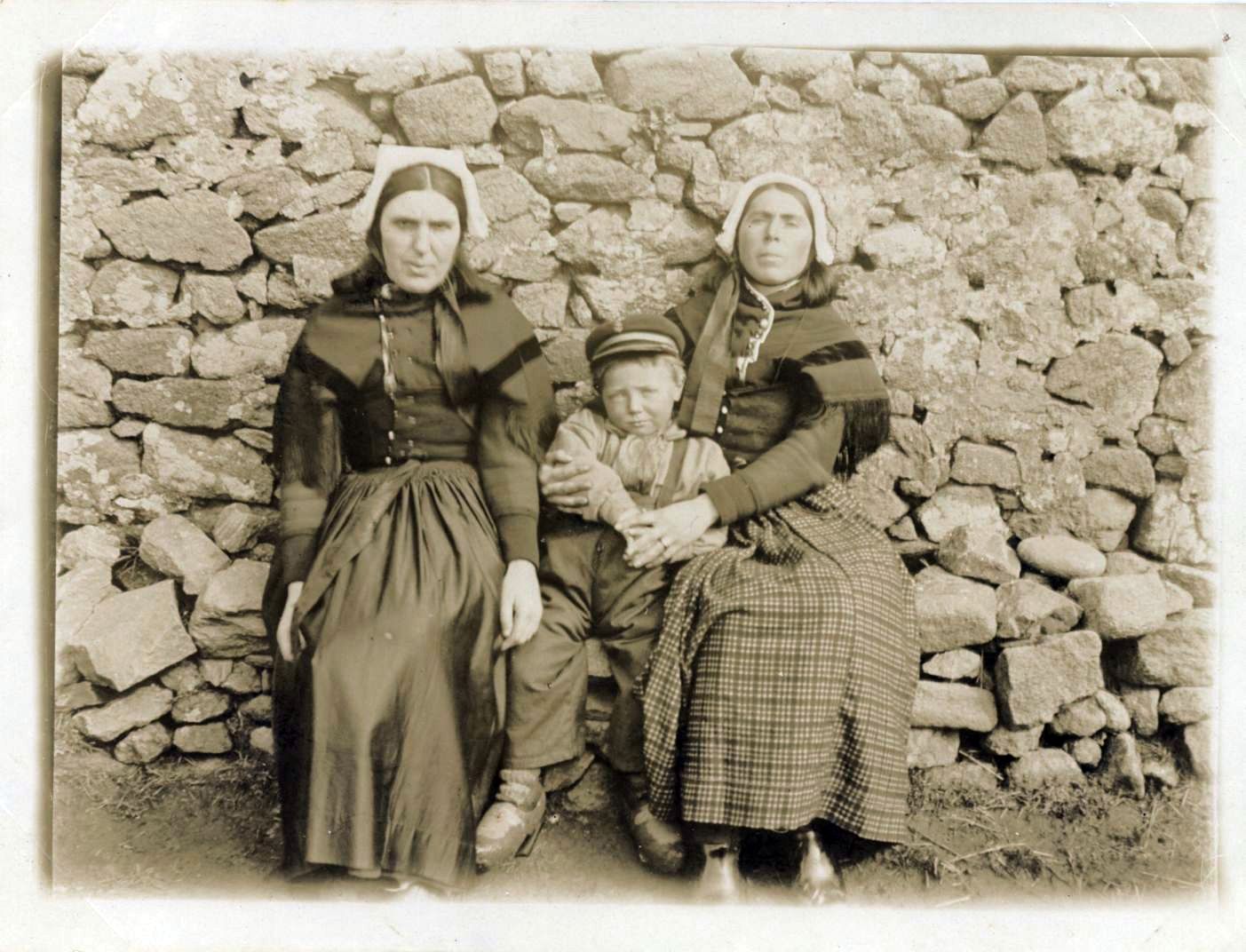 Photographie de deux femmes et un garçon portant une casquette de marin.